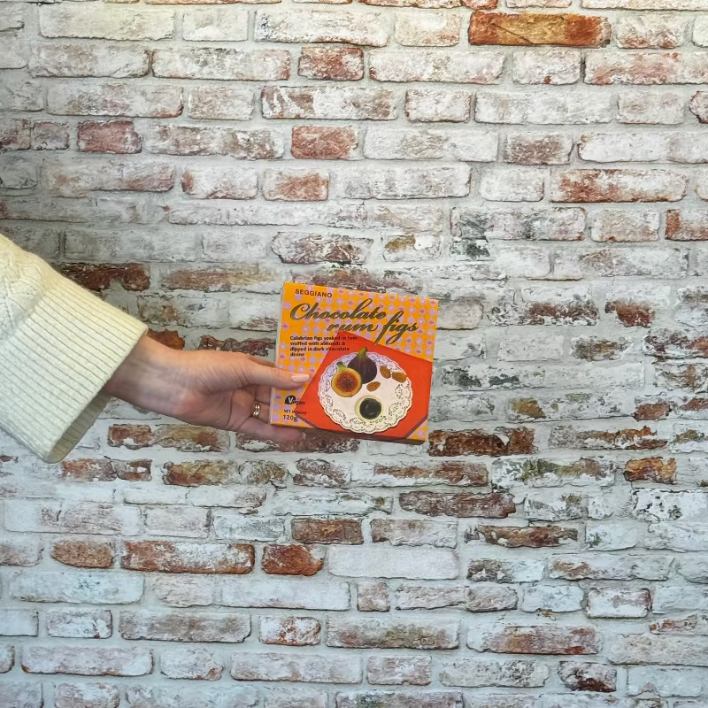 Person holding Chocolate Rum Figs against a brick wall.