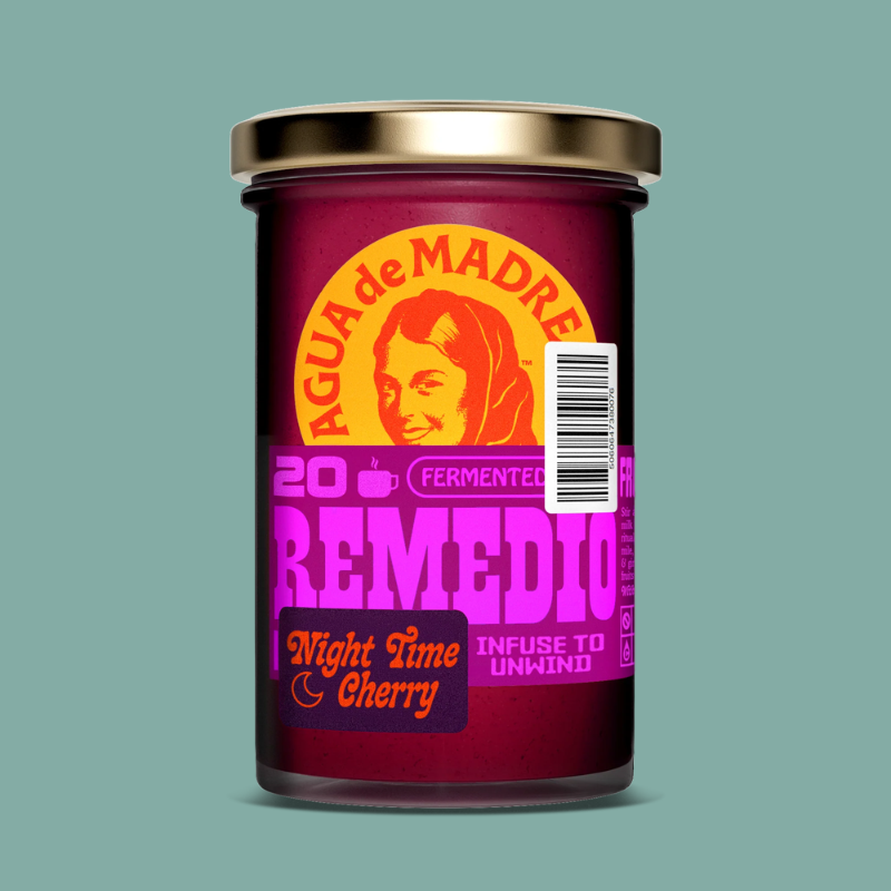 A glass jar with a metallic gold lid and a dark magenta label featuring the brand 'Agua de Madre' and the scent 'Night Time Cherry'. The label has a retro design with a stylized woman's face, a barcode, and bold text in orange and purple, set against a solid teal background.