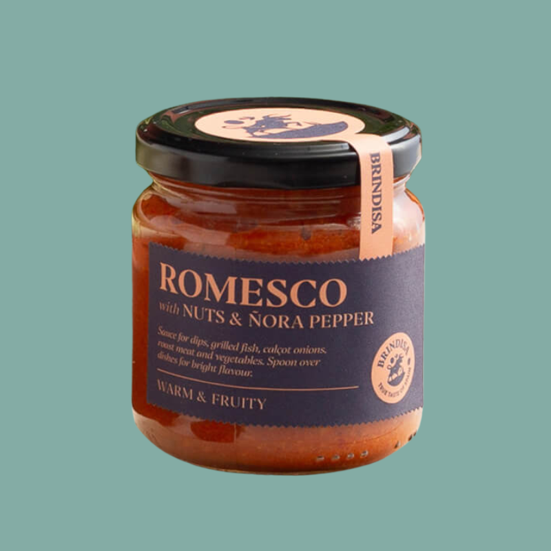 Jar of Romesco sauce with nuts and Nora pepper on a green background