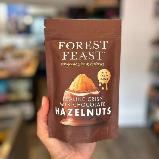 Hand holding a package of Forest Feast milk chocolate hazelnuts in a store setting