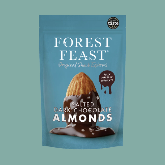 A blue stand-up pouch of Forest Feast Salted Dark Chocolate Almonds, featuring an illustration of an almond dipped in chocolate on the front, set against a solid teal background.