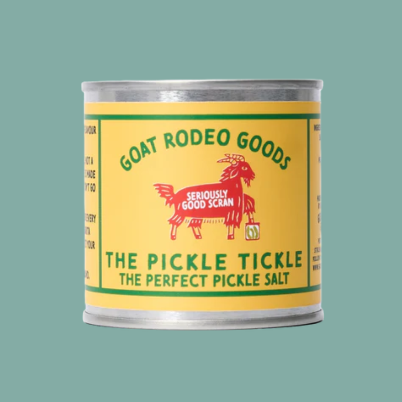 A vintage-style metal can of Goat Rodeo Goods 'The Pickle Tickle' pickle salt, featuring a bright yellow label with green text and a red goat illustration, set against a solid teal background.