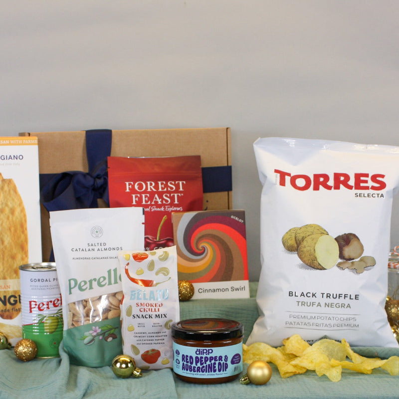 Collection of food products including a bag of Torres black truffle, Perelli cookies, and other snacks on a table.