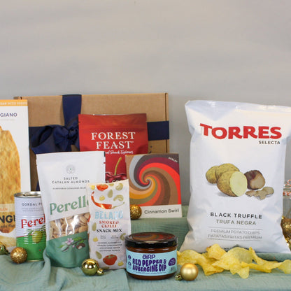 Collection of food products including a bag of Torres black truffle, Perelli cookies, and other snacks on a table.