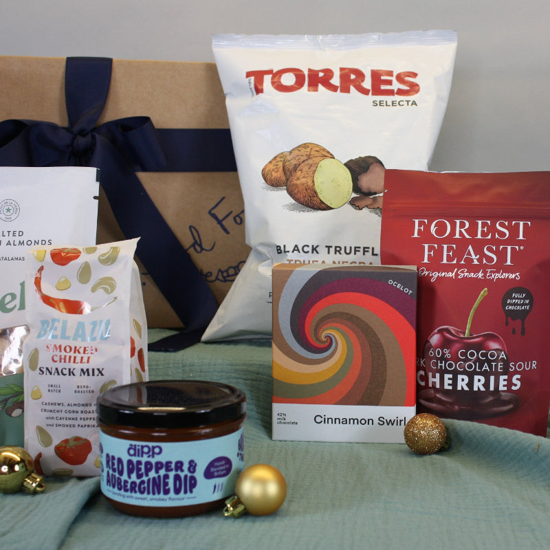Assorted food products including a jar, snack mix, and chocolate bars on a table.