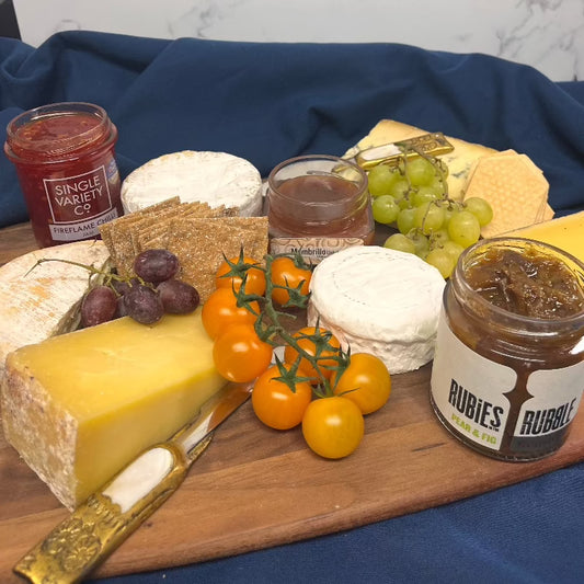 cheese board full of british farmhouse artisanal cheese with chutney grapes and peter yard crackers and a jar of fireflame chilli