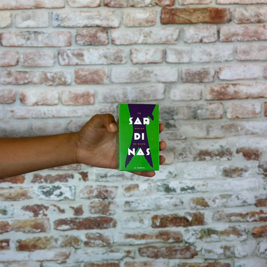 Hand holding La Narval 'Sardinas' branding against a brick wall.