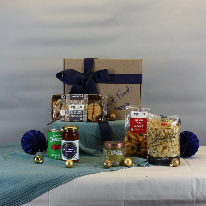 Gourmet gift basket with snacks and drinks on a table against a plain background