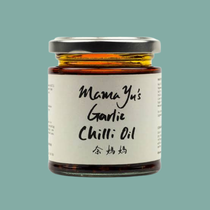 A glass jar of Mama Yu's Garlic Chilli Oil with a white label and silver lid, centered on a solid teal background.