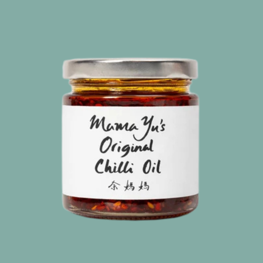 A glass jar of Mama Yu's Original Chilli Oil with a white label and silver lid, centered on a solid teal background.