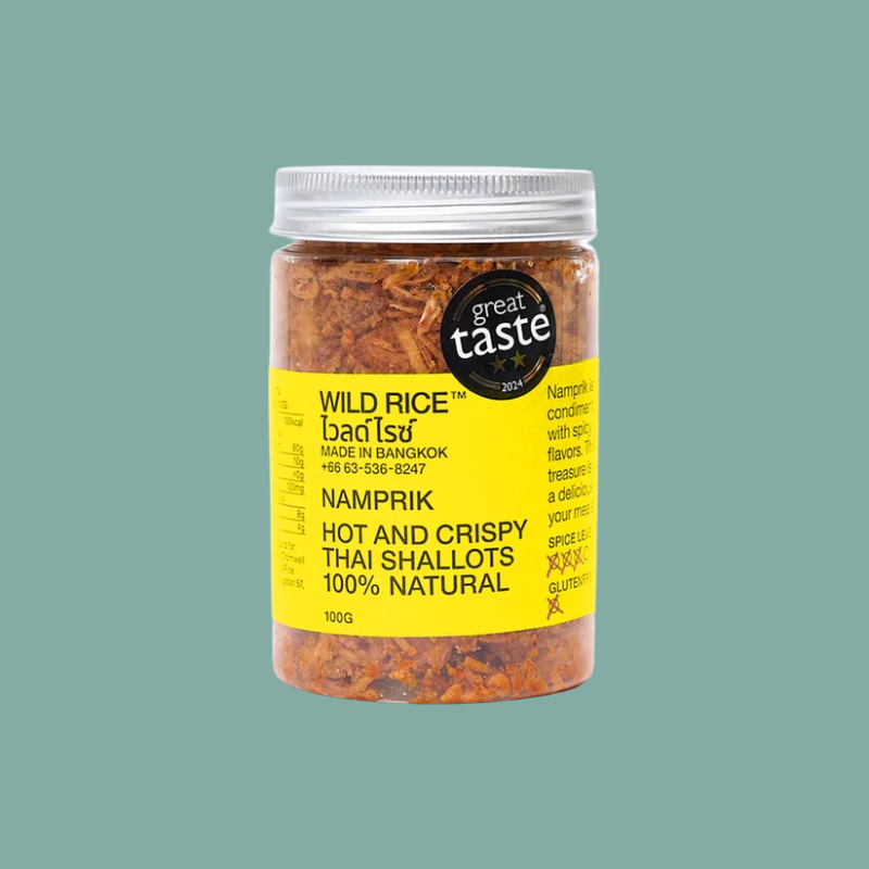 A 100g plastic jar of Great Taste Namprik Hot and Crispy Thai Shallots, filled with orange-red seasoning flakes, featuring a bright yellow label and a silver lid, set against a solid teal background.