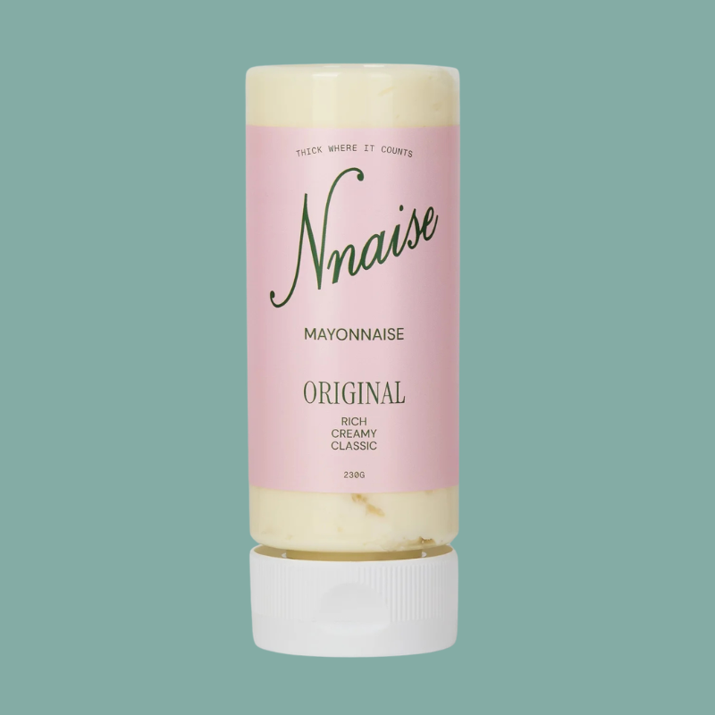 A squeeze tube of Nnaise Mayonnaise Original, featuring a light pink label and white cap, set against a solid teal background.