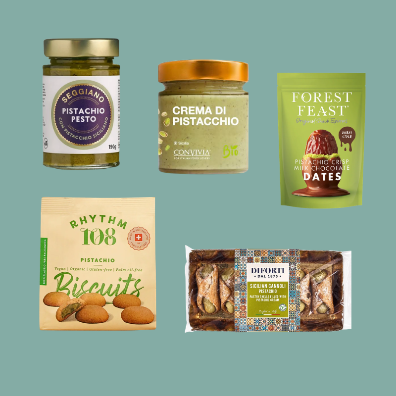 A collage of six different food products on a solid muted teal background: a jar of Seggiano pistachio pesto, a jar of Cornivia crema di pistacchio, a pouch of Forest Feast pistachio crisp mixed chocolate dates, a bag of Rhythm 108 pistachio biscuits, and a package of Diforti chocolate chip cookies with pistachio. Each product is shown clearly with its packaging visible.