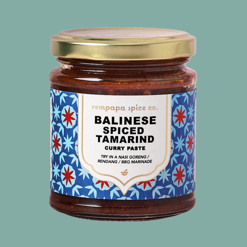 Jar of Balinese spiced tamarind curry paste with decorative label on a teal background