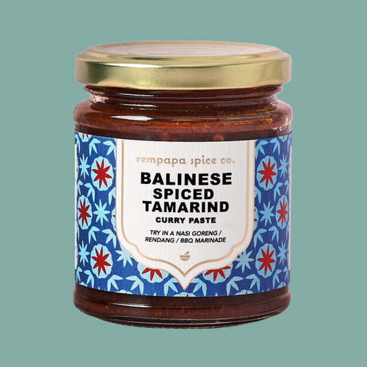 Jar of Balinese spiced tamarind curry paste with decorative label on a teal background