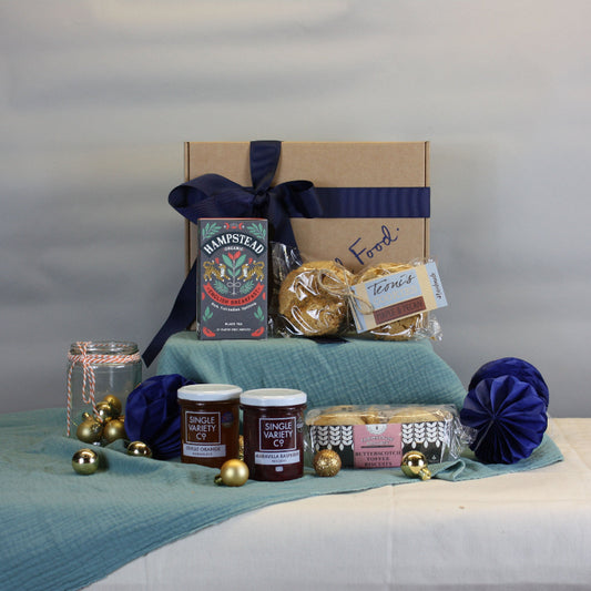Gourmet gift basket with items on a table against a plain background
