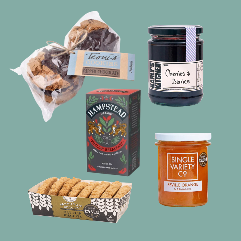 A curated gift basket of food products on a solid teal background, including a bag of Ripped Chocolate cookies, a jar of Cherries & Berries jam by Laura Walker, a box of Hampstead Black Tea, and a tin of Single Variety C9 Sevylle Orange Marmalade with a box of Ripped Biscuits.