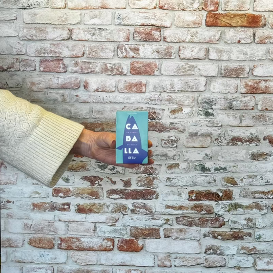 Person holding a tinned mackerel against a brick wall.