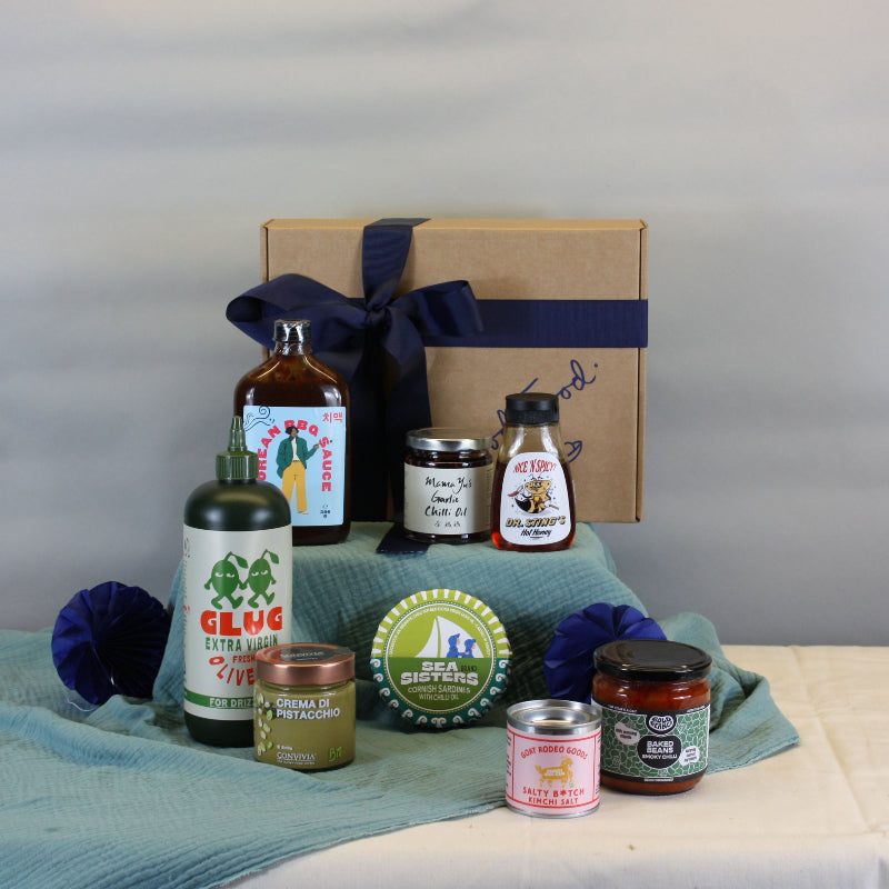 Collection of bottles and jars on a table with a box and decorative items against a plain background