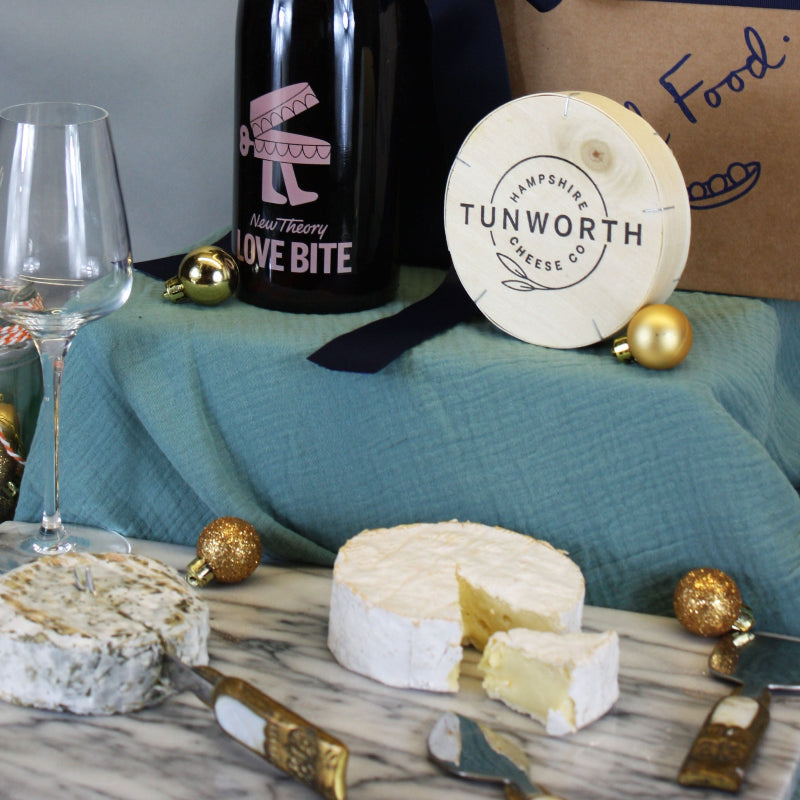 Bottle of wine, cheese, and crackers on a table with a box in the background